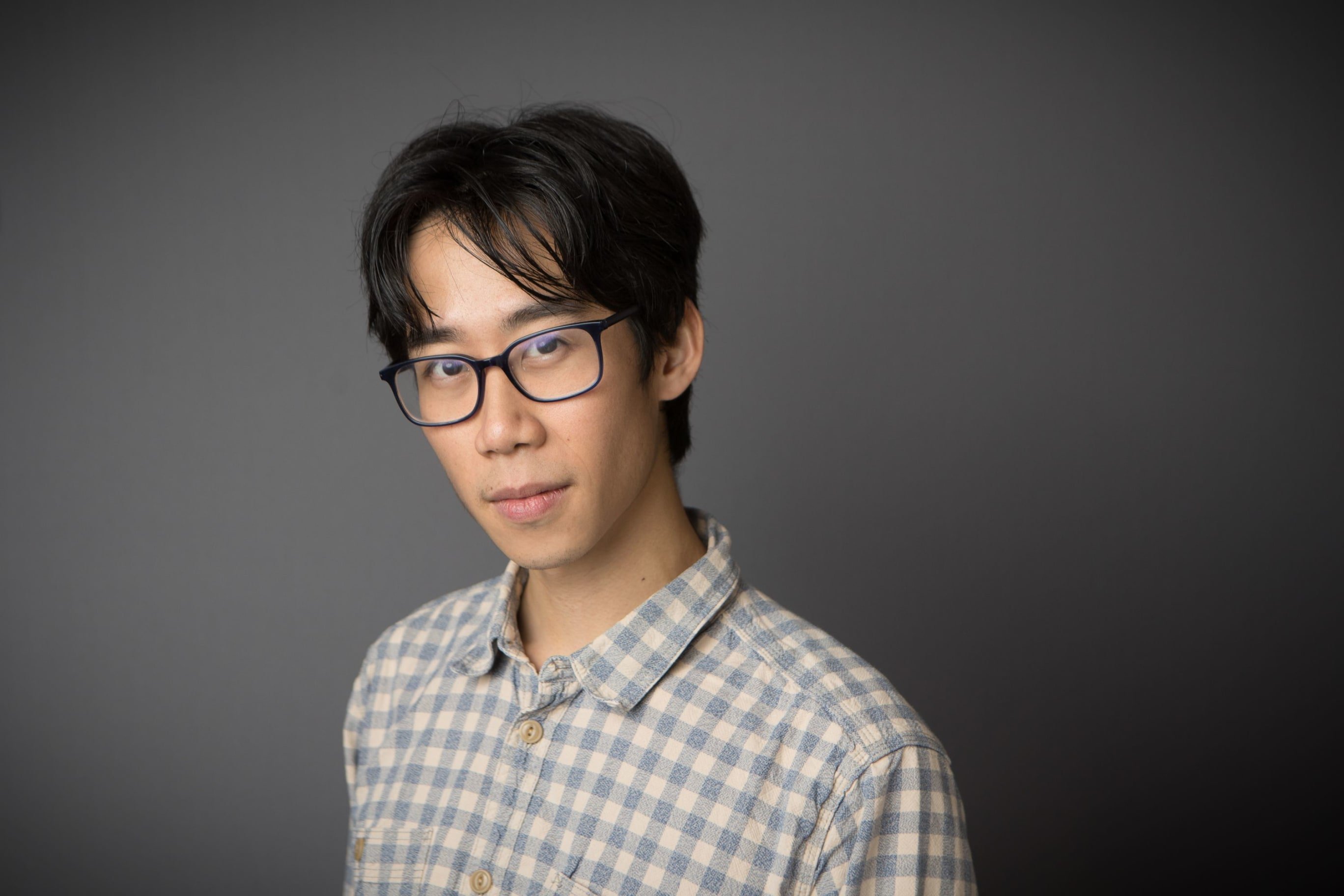 Headshot of Alex, an asian man with glasses and short dark hair with a long fringe